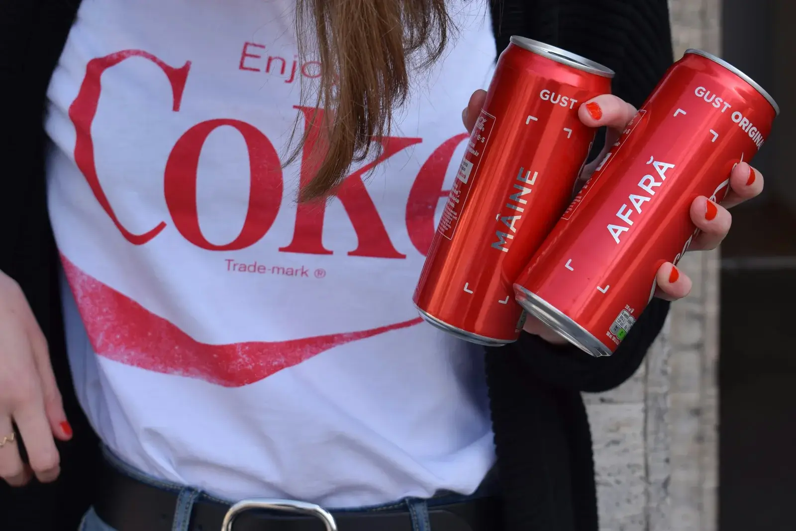 Hand holding Coca-Cola cans featuring custom, personalized packaging design